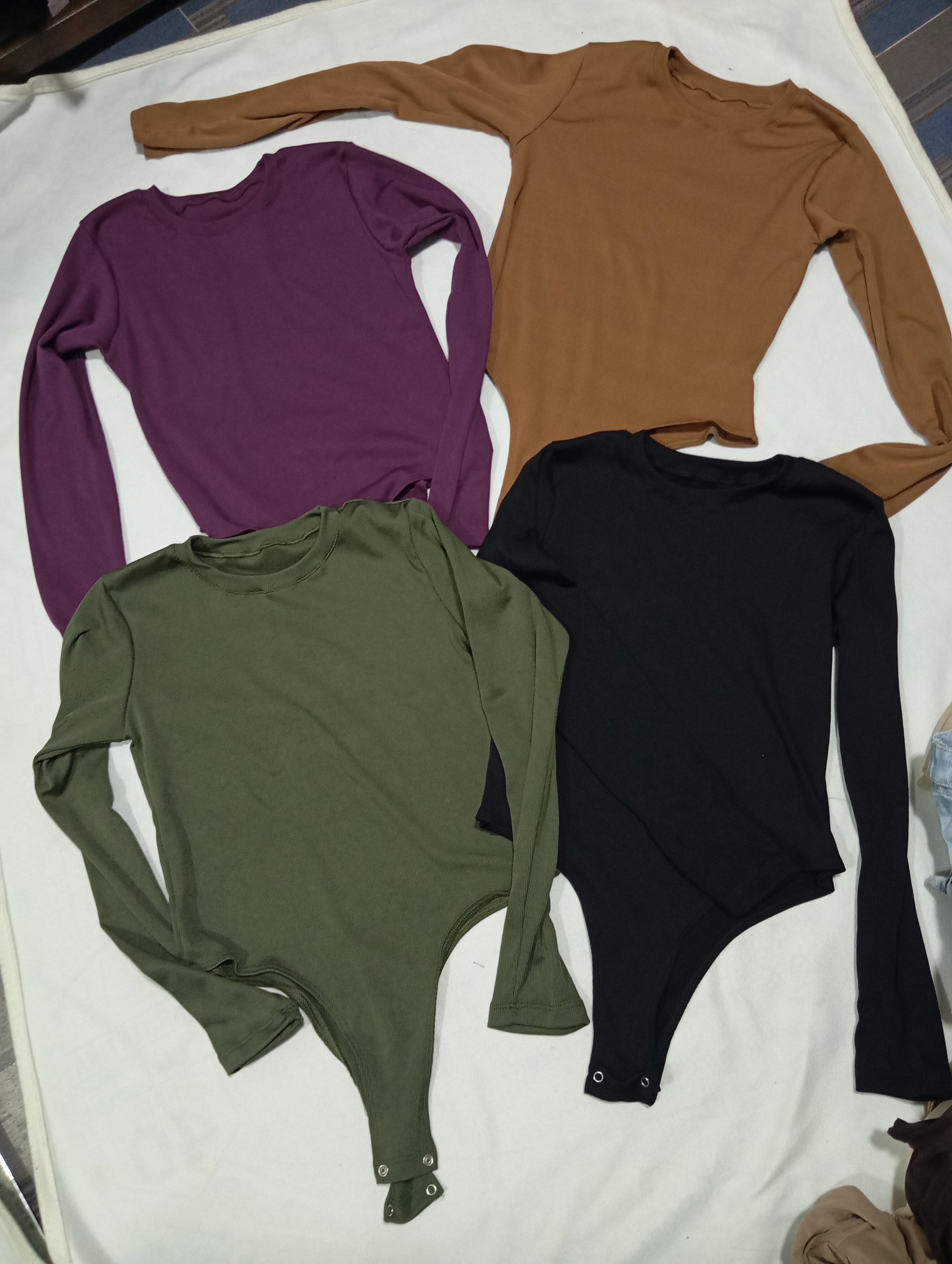 Cuatro bodys acanalados manga larga en colores lila, marrón, verde militar y negro