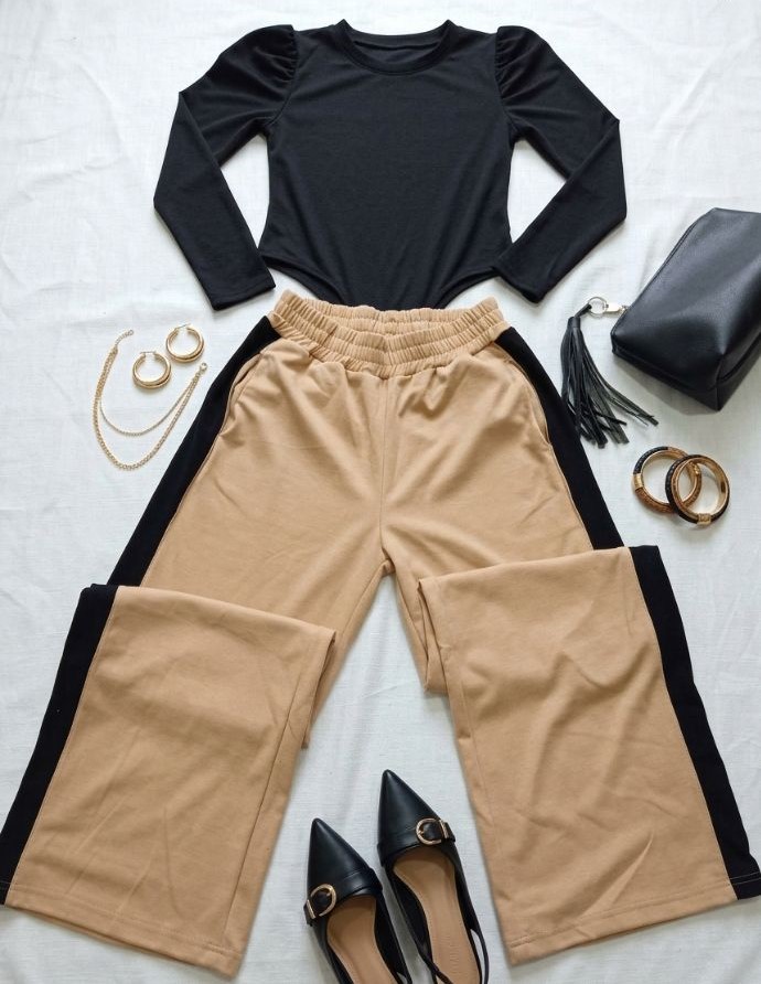 Pantalón sastrero beige con raya lateral negra, top negro de manga larga, zapatos y cartera negra